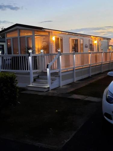 a house with a porch and a white railing at Millfields 4 berth caravan DG & CH family's only and lead person must be over 30 in Ingoldmells