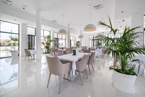 a restaurant with white tables and chairs and plants at Miramare Hotel in Zadar