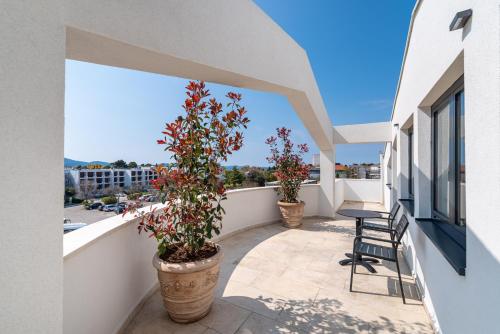 a balcony with two potted plants and a table and chairs at Miramare Hotel in Zadar