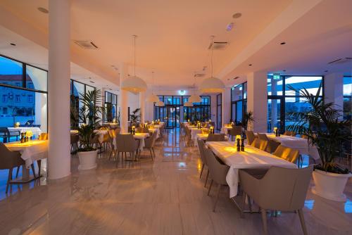 a restaurant with tables and chairs and windows at Miramare Hotel in Zadar
