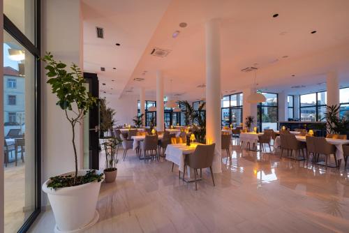 a dining room with tables and chairs and windows at Miramare Hotel in Zadar
