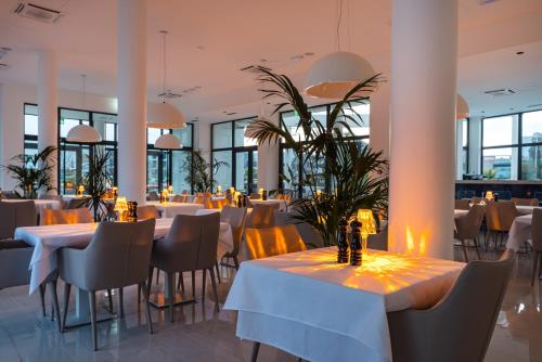 a dining room with tables and chairs and windows at Miramare Hotel in Zadar