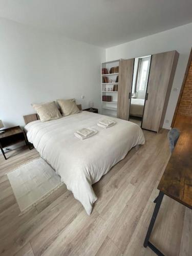 een slaapkamer met een groot wit bed en houten vloeren bij Agréable maison de ville in Saujon