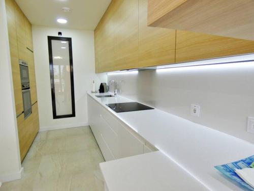 uma cozinha branca com um lavatório e um balcão em London Beach Benidorm em Finestrat
