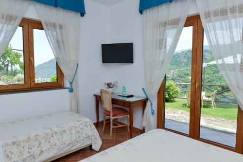 Zimmer mit 2 Betten und einem Schreibtisch mit Fenster in der Unterkunft Villevieille in Piano di Sorrento