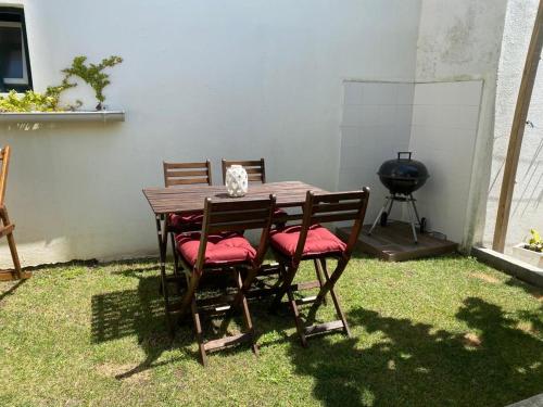 a wooden table with four chairs and a grill at Casas dos Seixos in Moledo