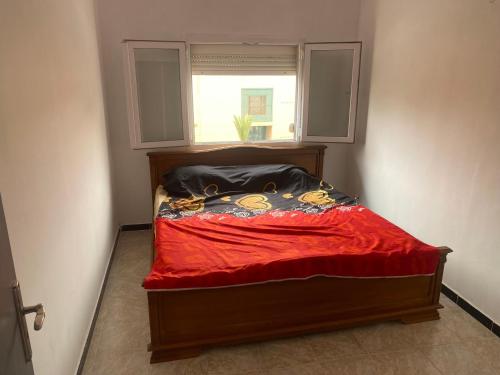 łóżko z czerwonym kocem i oknem w obiekcie Akid w mieście Oran