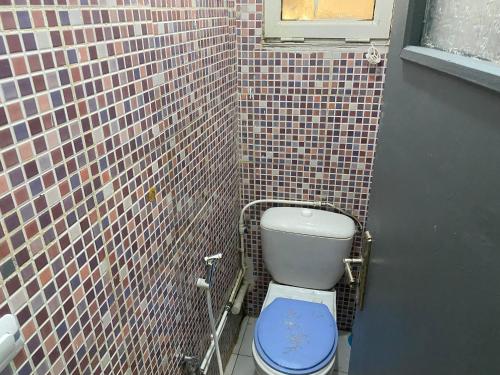 a bathroom with a toilet with a tiled wall at Akid in Oran