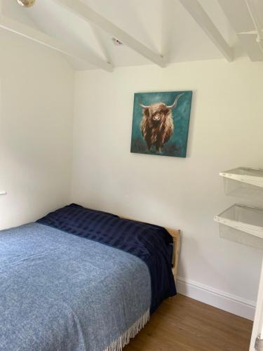 a bedroom with a bed with a picture of a bull on the wall at Garden Annexe in Kinsham