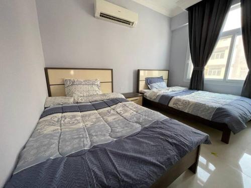 a bedroom with two beds and a window at Fully Furnished 2bedroom apartment, Salalah, Oman in Salalah