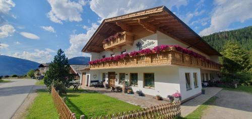 a house with a balcony with flowers on it at Enzian Apartments in Kartitsch