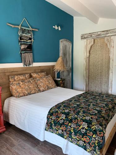 a bedroom with a large bed with blue walls at La villa Paloma in Sylvéréal