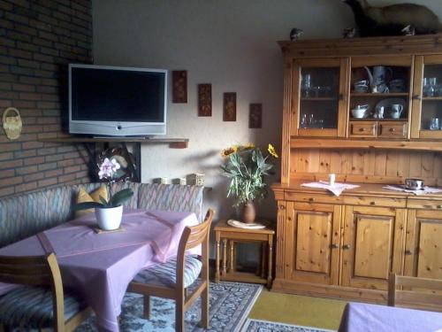 a living room with a table and a tv on a wall at Pension Familie Schwarz GbR in Alhausen