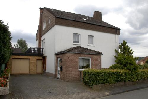a white and red house with a driveway at Pension Familie Schwarz GbR in Alhausen