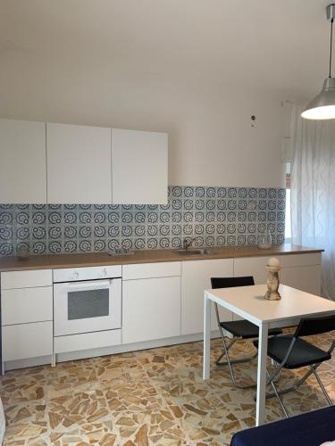 een keuken met witte kasten en een tafel met stoelen bij Casa Luce in Brindisi di Montagna