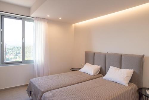 a bedroom with a bed with two pillows and a window at Sunset Luxury Villa in Akritokhórion