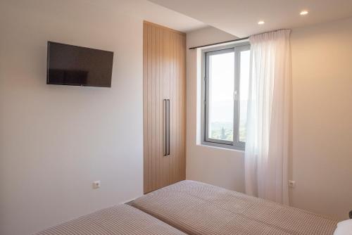 a bedroom with a bed and a tv and a window at Sunset Luxury Villa in Akritokhórion