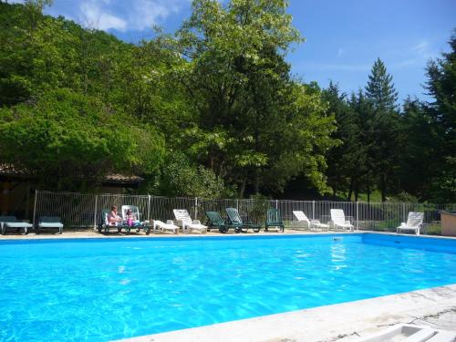 a woman sitting in a chair next to a swimming pool at Gîtes du Domaine de Serre Long in Saint-Maurice-dʼIbie