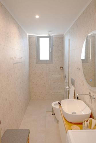 a bathroom with a sink and a toilet and a mirror at Sunset Luxury Villa in Akritokhórion