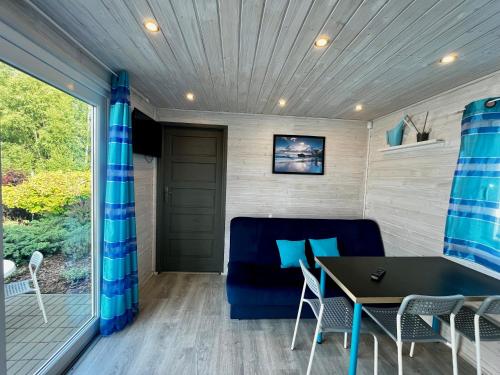 a tiny house with a blue couch and a table at Domki Baltyk in Dąbki