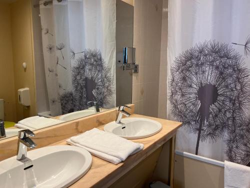 a bathroom with two sinks and a shower curtain at Hôtel Le Lacuzon in Moirans-en-Montagne