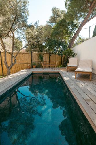 - une piscine avec une terrasse en bois, une table et des chaises dans l'établissement Le Resort, charmante petite villa d'architecte, à Saint-Jean-de-Védas