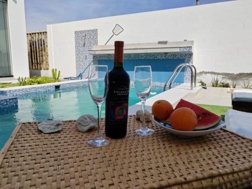 a bottle of wine and glasses on a table next to a pool at Albamar - Casa Antonio - Beach house in El Ñuro