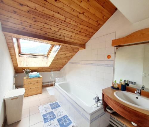 a bathroom with a white tub and a sink at Au Pré du Moulin - 5 MINUTES DES PISTES in Briançon