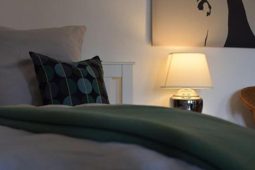 a bed with a green blanket and a lamp at Backnanger Terrassenstüble in Backnang