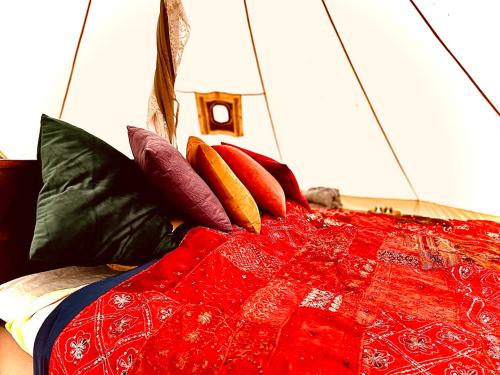 una cama con almohadas coloridas encima en tent delhi a b&b in a luxury glamping style en Mariefred
