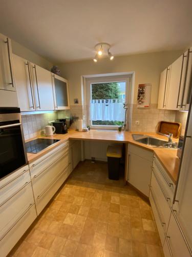 eine Küche mit weißen Schränken und einem Fenster in der Unterkunft Eichendorff Garten Apartment, zentrumsnah, in direkter Nähe zur Universität in Bayreuth