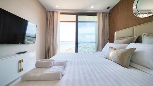 een slaapkamer met een groot wit bed en een groot raam bij Copacabana Beach Jomtien in Jomtien Beach