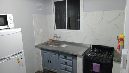 uma cozinha com um lavatório, um fogão e um micro-ondas em Dpto Saavedra em Tres Arroyos