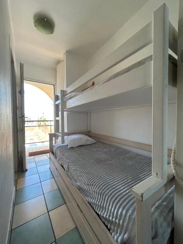 sypialnia z dwoma łóżkami piętrowymi i oknem w obiekcie Studio Vue Mer situé à côté de la plage Quartier des Quilles w mieście Sète