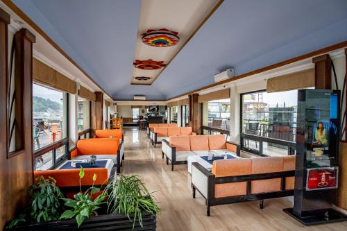 uma sala de espera com cadeiras laranja e janelas em Hotel Sarowar em Pokhara