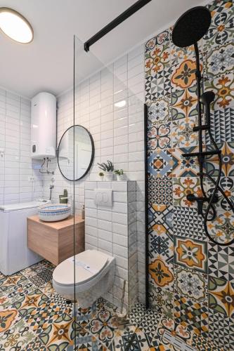 a bathroom with a shower and a toilet and a tile wall at Villa Nika in Novalja