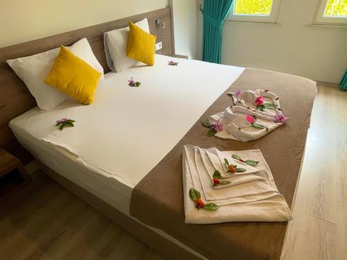 a bed with two towels and some flowers on it at Güneş Boutique Hotel - Oludeniz in Oludeniz