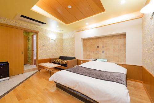 1 dormitorio con 1 cama y 1 silla en una habitación en ホテルシエル東静岡店 -大人専用-, en Shizuoka