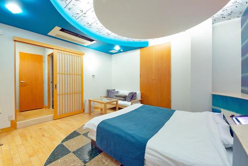 1 dormitorio con 1 cama grande y techo azul en ホテルシエル東静岡店 -大人専用-, en Shizuoka