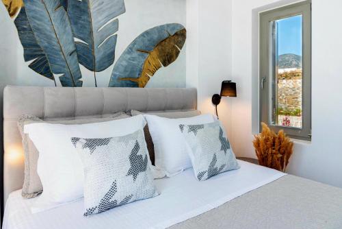 a bedroom with a bed with white pillows and a window at Golden Bay luxury villas and suites in Chrissi Akti