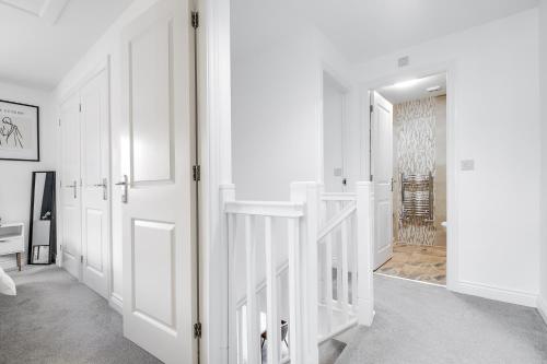 un corridoio bianco con porte bianche e una scala di Contractors Retreat 3 bed house, sleeps up to 7, free parking a Milton Keynes