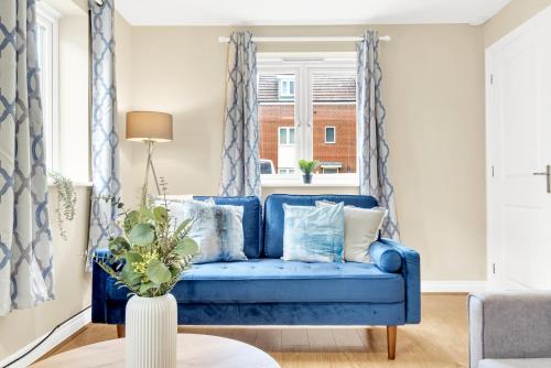 a blue couch in a living room with a window at Contractors Retreat 3 bedroom house, sleeps up to 7, free parking in Milton Keynes