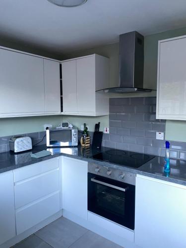 uma cozinha com armários brancos e um forno com placa de fogão em Comfy Darlington Home em Darlington