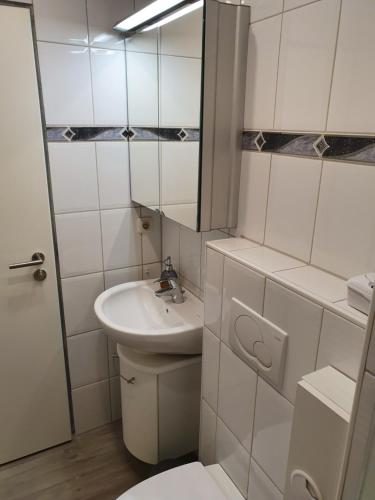 W łazience znajduje się umywalka, toaleta i lustro. w obiekcie Kleine Milchbar w mieście Norderney