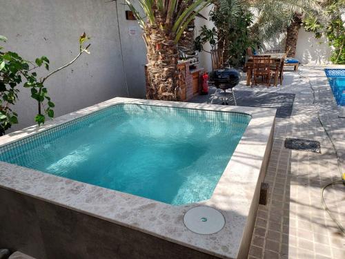 - une piscine dans un jardin avec une table et des chaises dans l'établissement Dar 66 Pool Chalets with Jacuzzi, à Ras al Khaimah