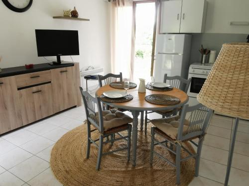 a kitchen with a table with chairs and a television at L'enclos bleu, gîte - marais poitevin avec piscine chauffée in Chaillé-les-Marais