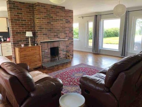 a living room with a couch and a brick fireplace at Harbour View Cottage, Rochespoint, Cork Harbour in Midleton