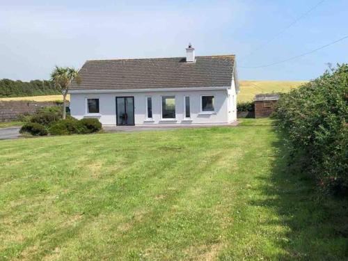 a small white house with a grass yard at Harbour View Cottage, Rochespoint, Cork Harbour in Midleton