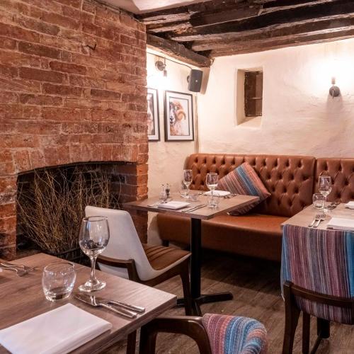 a restaurant with tables and a couch in a brick wall at Wisteria Hotel in Oakham
