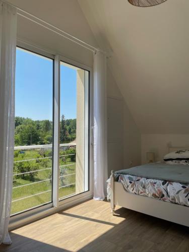 ein Schlafzimmer mit einem Bett und einem großen Fenster in der Unterkunft Le Verger de Sophie in Sainte-Geneviève-lès-Gasny